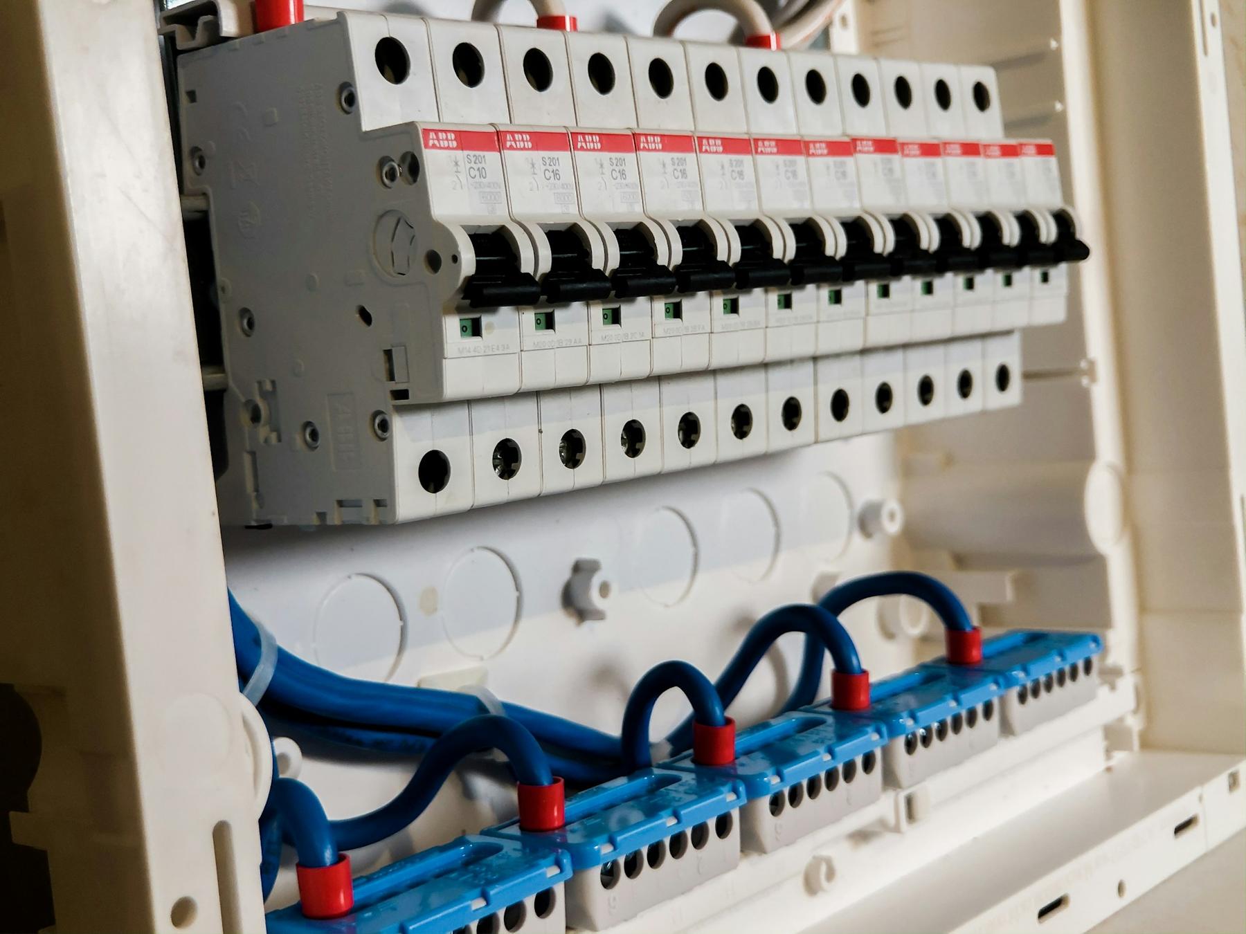 Close-up of an open breaker panel with a row of white circuit breakers and neatly routed blue wiring
